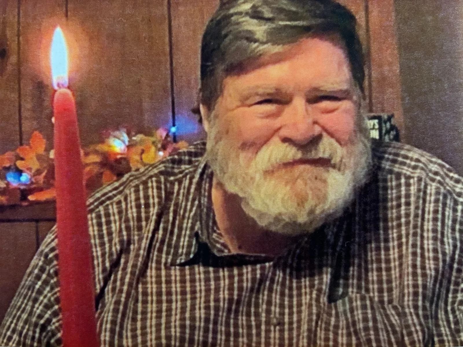 Uncle Larry smiling beside a glowing red candle at a family gathering